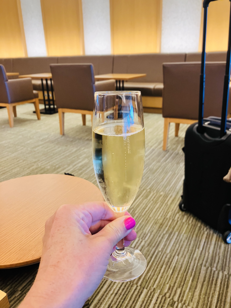 hand holding a glass of champagne in an airport lounge